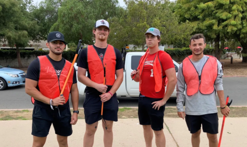 Four cleanup volunteers pose with high visibility vests and cleanup tools