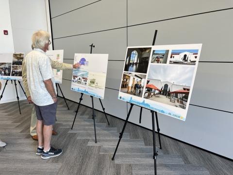 Two people standing in front of poster boards showcasing development plans for the airport.