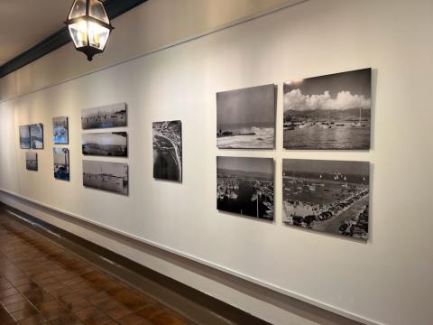 image shows photographs on the wall on the first floor of City hall, the exhibit is titled Tides of Time: Collaboration with the Santa Barbara Maritime Museum, the new City Hall Gallery exhibition. This exhibition includes historical photographs of the development of the Santa Barbara Harbor, which is one of the last working harbors in the state. The show also includes photos from Our Channel Islands by Ernest H. Brooks II, who is renowned for his innovative underwater photography techniques.