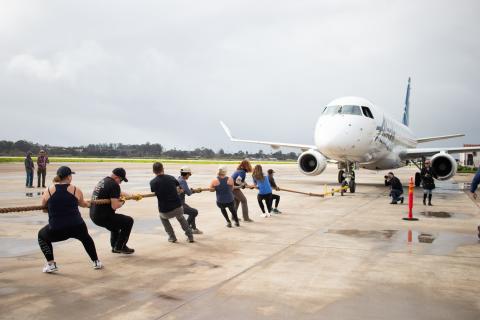 A group of people pull an airplane by a rope.