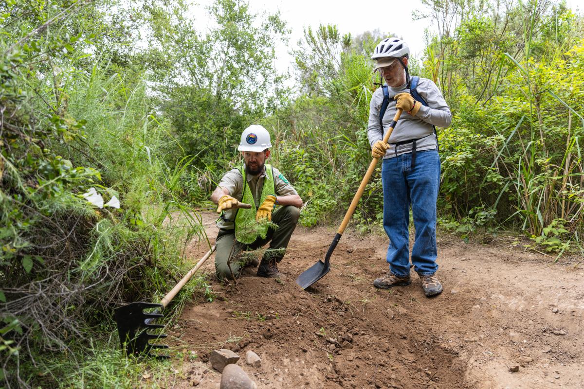 Trail volunteer learns from staff member as they work on Jesusita Trail